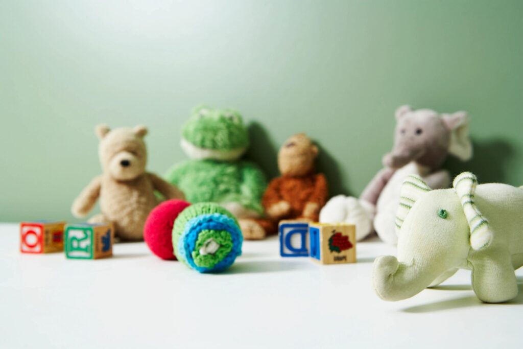 Children's toys, including stuffed animals and wooden blocks are seen against a light green wall