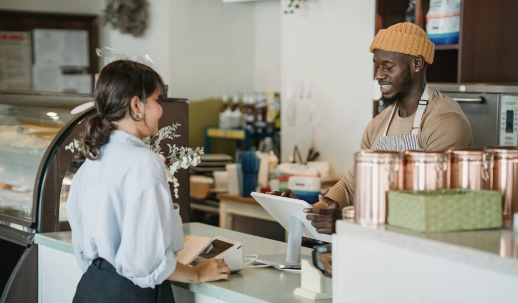 A teen orders a drink from a barista at a coffee shop